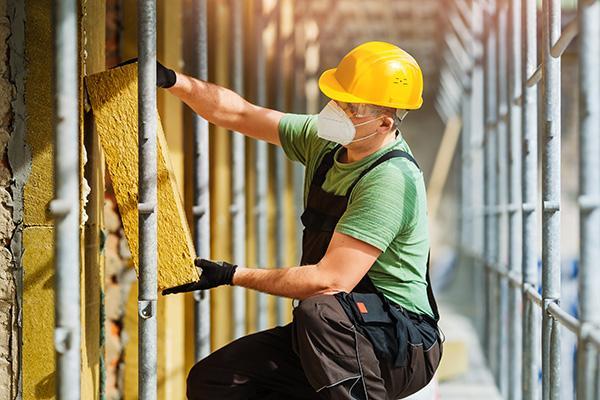 Architekt mit Bauplänen und Tablet auf einer Baustelle